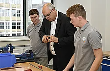 Bürgermeister Andreas Bovenschulte unterhält sich mit zwei Auszubildenden der Ausbildungswerkstatt der Deutschen Bahn im Bremer HAG-Quartier.