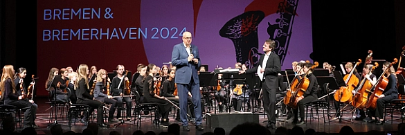 Bürgermeister Andreas Bovenschulte  steht auf der Bühne und spricht beim Orchesterfestival in Bremerhaven 2024.  Bürgermeister Andreas Bovenschulte  steht auf der Bühne und spricht beim Orchesterfestival in Bremerhaven 2024.