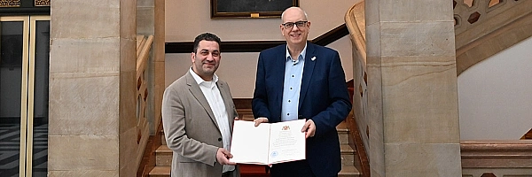 Bürgermeister Andreas Bovenschulte überreicht dem neuen Honorarkonsul für Gambia, Basem Khan, die Ernennungsurkunde. 