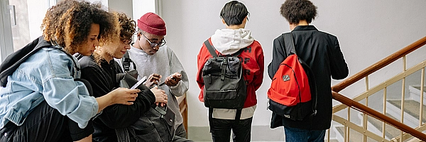 Jugendliche in einem Schul-Treppenhaus mit Handys.