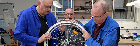 Sven Nollmann zeigt Bürgermeister Bovenschulte die Arbeitsschritte bei der Reparatur eines Rollstuhlreifens.