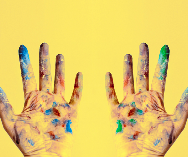 Symbolbild: gelbe Hände mit Farbe bekleckst