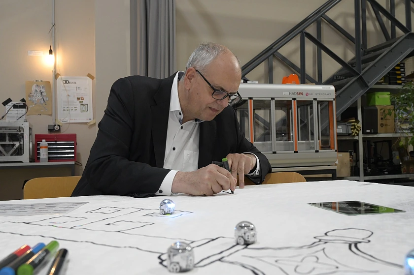 Mit verschiedenen Farben programmiert Bürgermeister Bovenschulte auf einem Stück Papier die Laufrichtung des Mini-Roboters Ozobot.